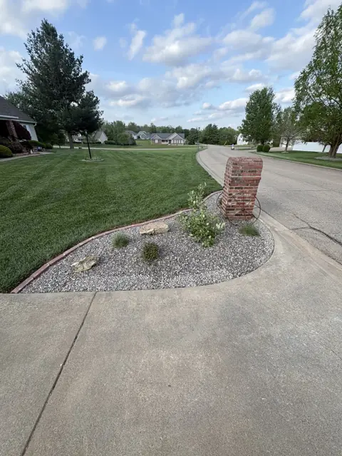 Completed mailbox bed with decorative rock, plants, and stone edging